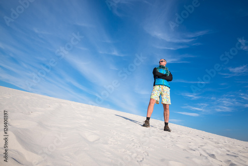 Man hiker, wearing sunglasses, relaxing in the desert