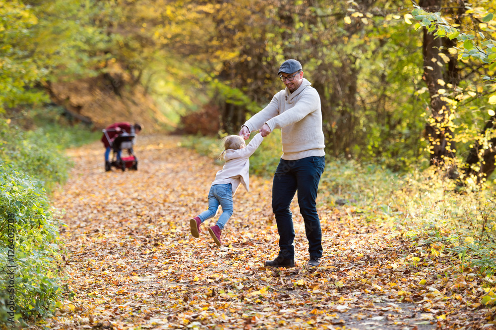 Fototapeta premium Beautiful young family on a walk in autumn forest.
