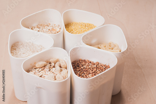 Collection of cereals, grains: rice, oats, buckwheat, millet, wooden table, country kitchen, white capacity,