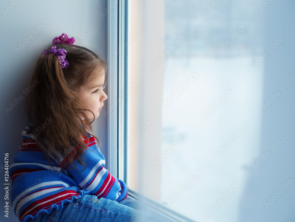 Little girl look out of the window