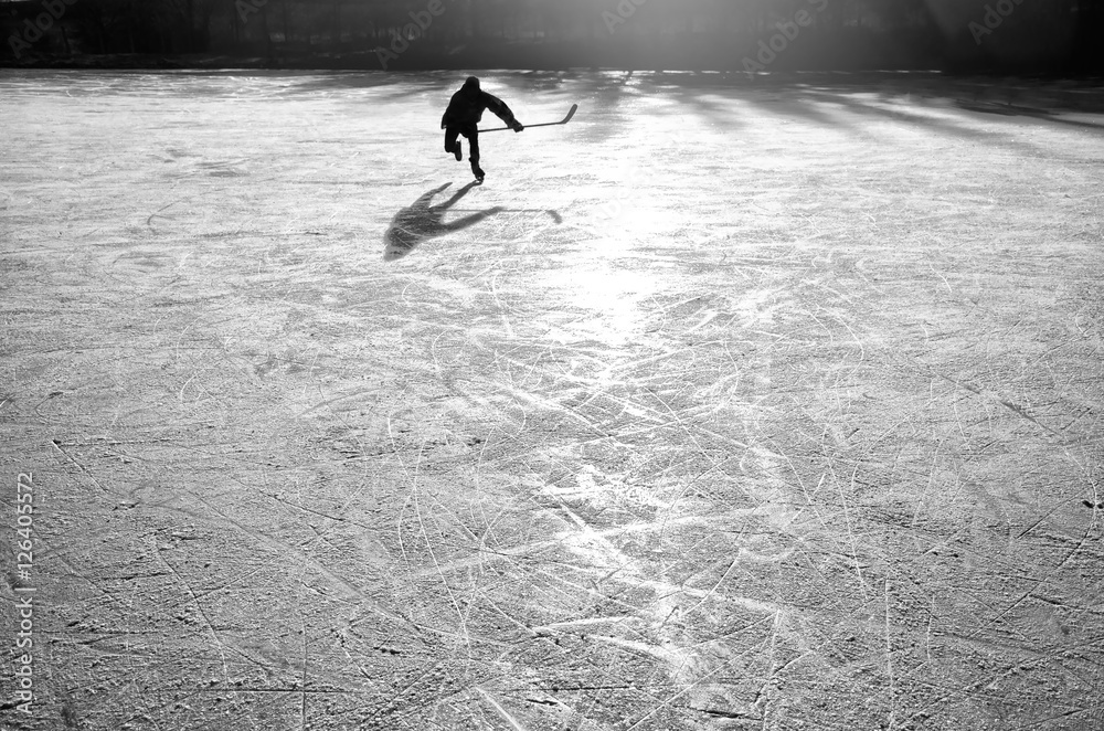 Fototapeta premium hockey player on the ice on sunset - black and white photo