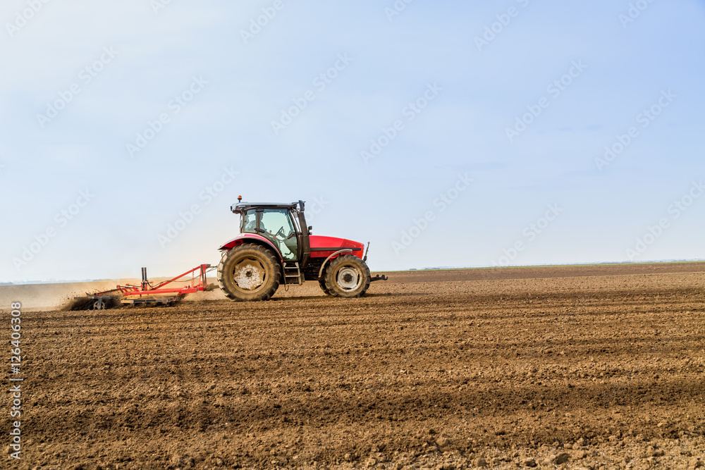 Farmer in tractor preparing land with seedbed cultivator Farmer in tractor preparing land with seedbed cultivator