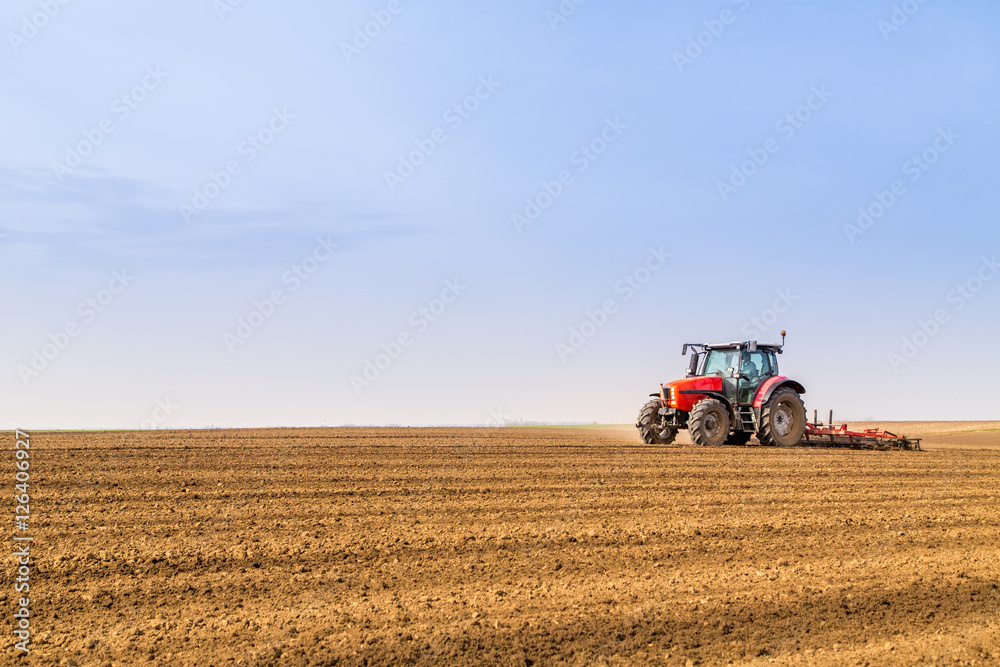 Farmer in tractor preparing land with seedbed cultivator Farmer in tractor preparing land with seedbed cultivator