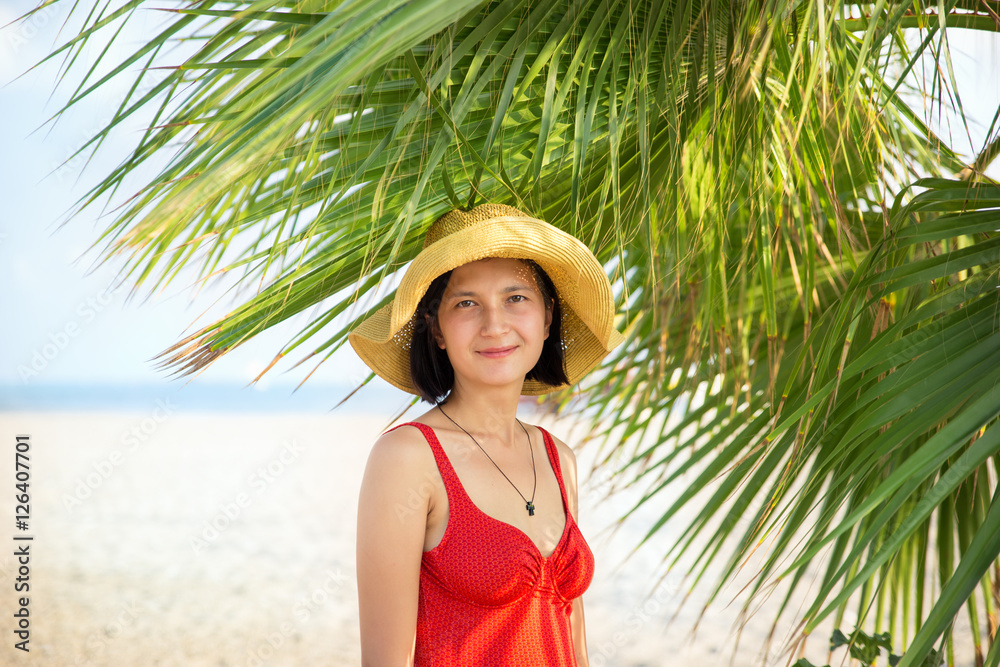 Smiling young woman wearing hat under the palm trees