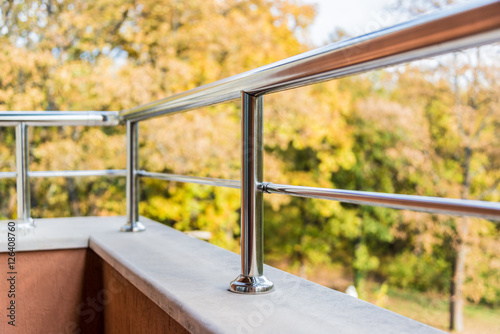 Close up of a balcony metal balustrade. Autumn view in the background.