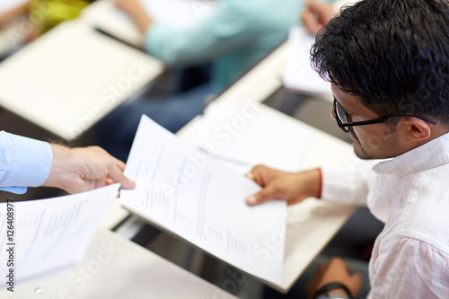 teacher giving exam test to student at lecture