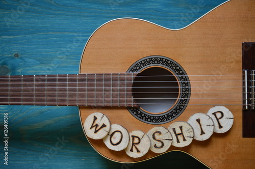 guitar on teal wooden background with wood pieces on it lettering the word: WORSHIP photo