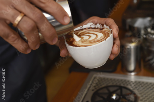 barista preparing coffee cream pouring milk in mug decorating with foam