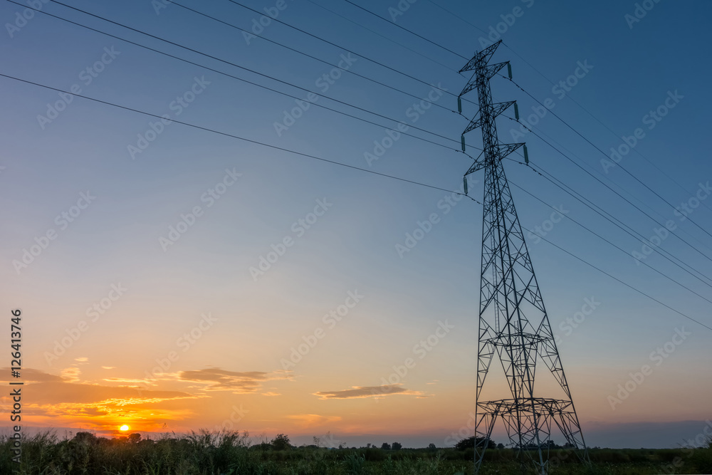 High voltage power pylons in the field at sunset