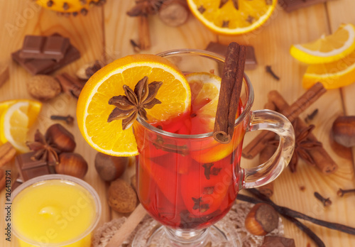 Mulled wine, orange, honey, nuts and sweets on light wood.