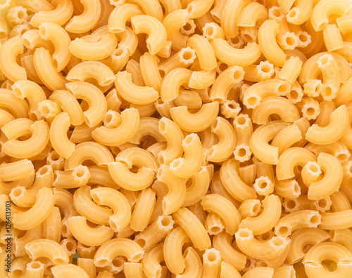 Yellow pasta in form of curved tubes closeup. Texture.