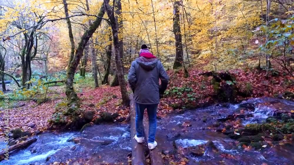 BOLU, TURKEY - NOVEMBER 08, 2016: Boy crossing on wood over river in Yedigoller. Yedigoller, also known seven lakes, is national park in Bolu, Turkey. BOLU, TURKEY - NOVEMBER 08, 2016: Boy crossing on wood over river in Yedigoller. Yedigoller, also known seven lakes, is national park in Bolu, Turkey.