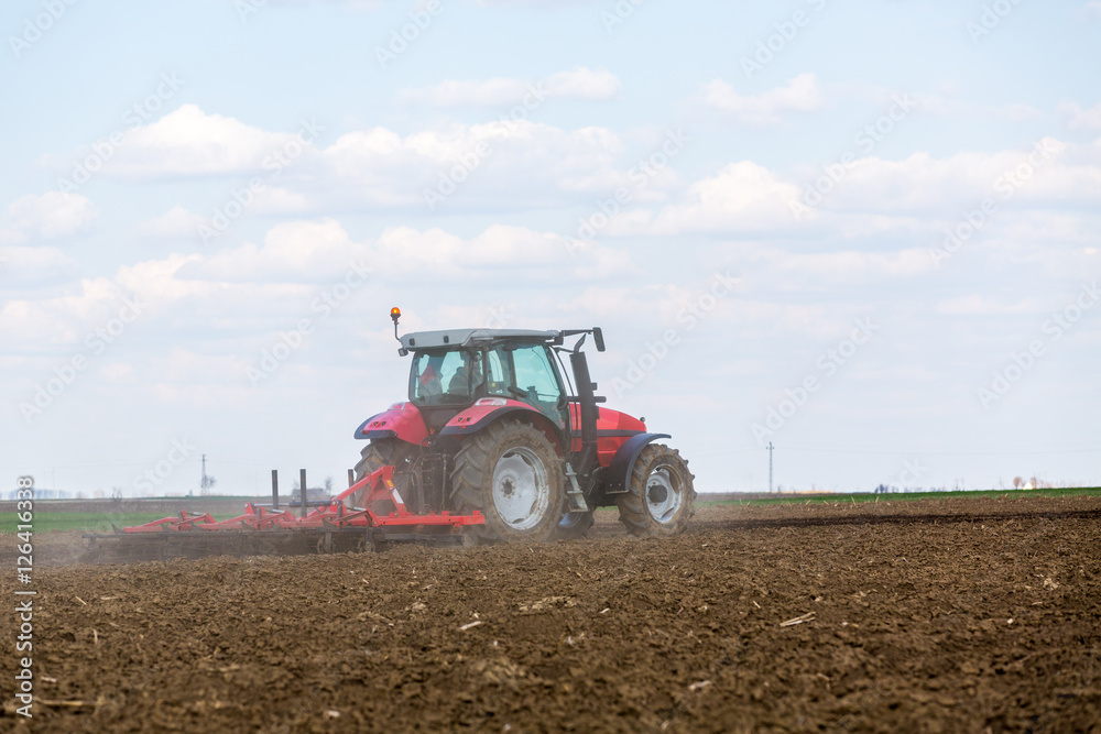 Farmer in tractor preparing land with seedbed cultivator Farmer in tractor preparing land with seedbed cultivator