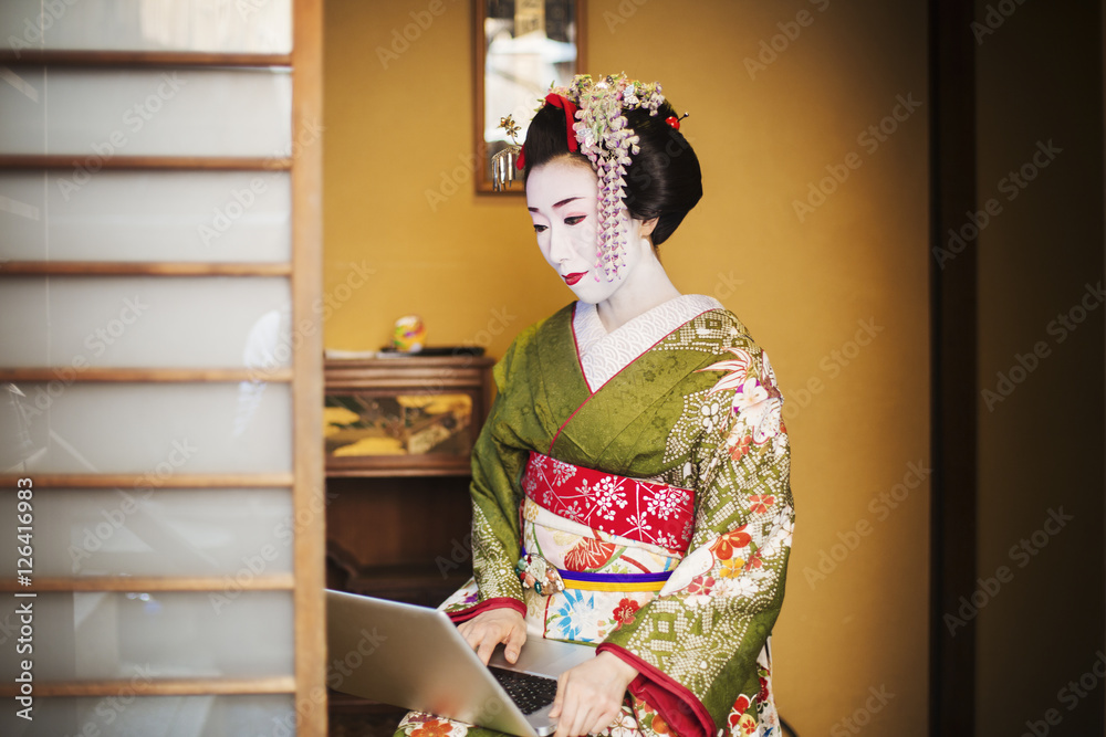 A woman dressed in the traditional geisha style, wearing a kimono and obi,  with an elaborate