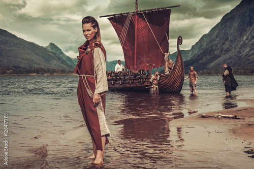 Foto Viking woman standing near Drakkar on seashore