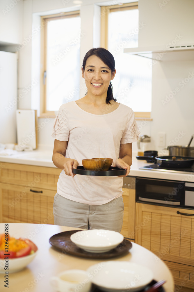 Family home. A woman preparing a meal arranging dishes on a table. Family home. A woman preparing a meal arranging dishes on a table.