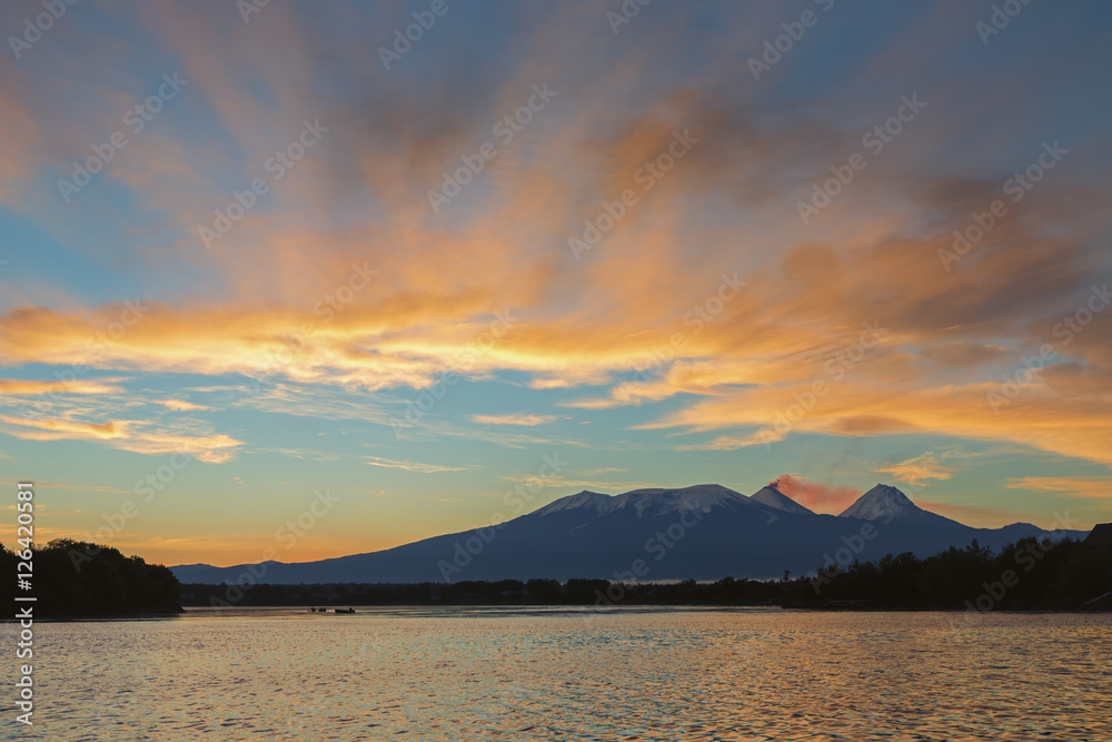 Beautiful sunrise over volcanoes Kluchevskaya group with reflection in the river Kamchatka.