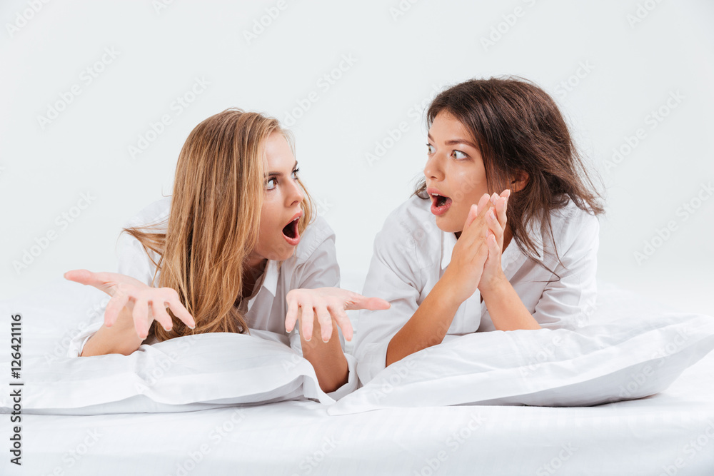 Women lying on bed and looking at each other Women lying on bed and looking at each other