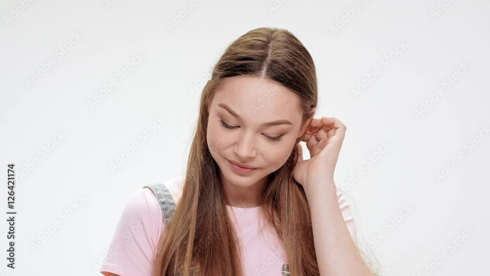 Shy young beautiful girl smiling over white background. Slow motion. Shy young beautiful girl smiling over white background. Slow motion.