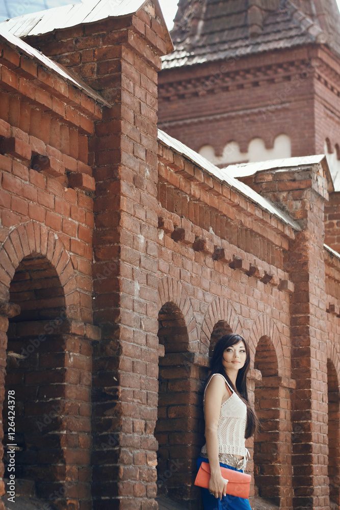 beautiful and charming young woman stands near the brick wall