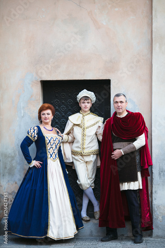 Beautiful family in medieval clothes posing in old town