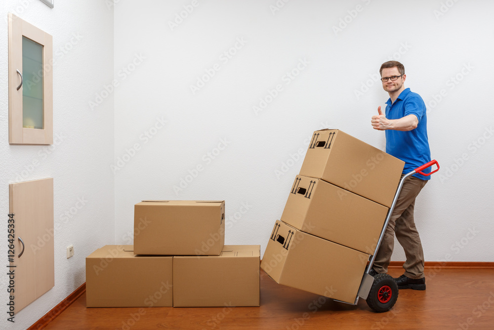 Mann packt Kartons auf eine Sackkarre Mann packt Kartons auf eine Sackkarre