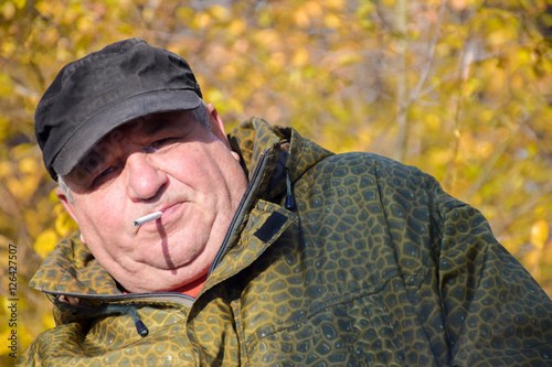 Mature caucasian man smoking cigarette outside