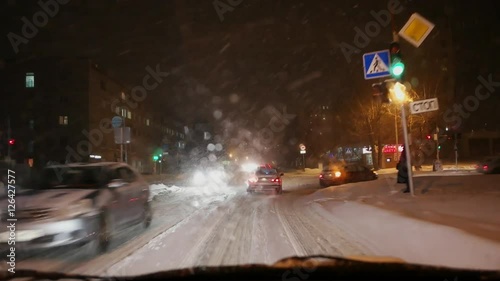 Driving a car through roadcross at night snowstorm photo