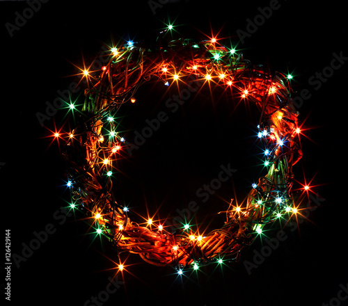 Winter holidays template card with copyspace isolated on black background. Wreath and garlands of colored light bulbs. Concept frame for shops label circle place for best price.