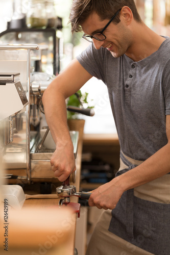 Young man as barista in cafe