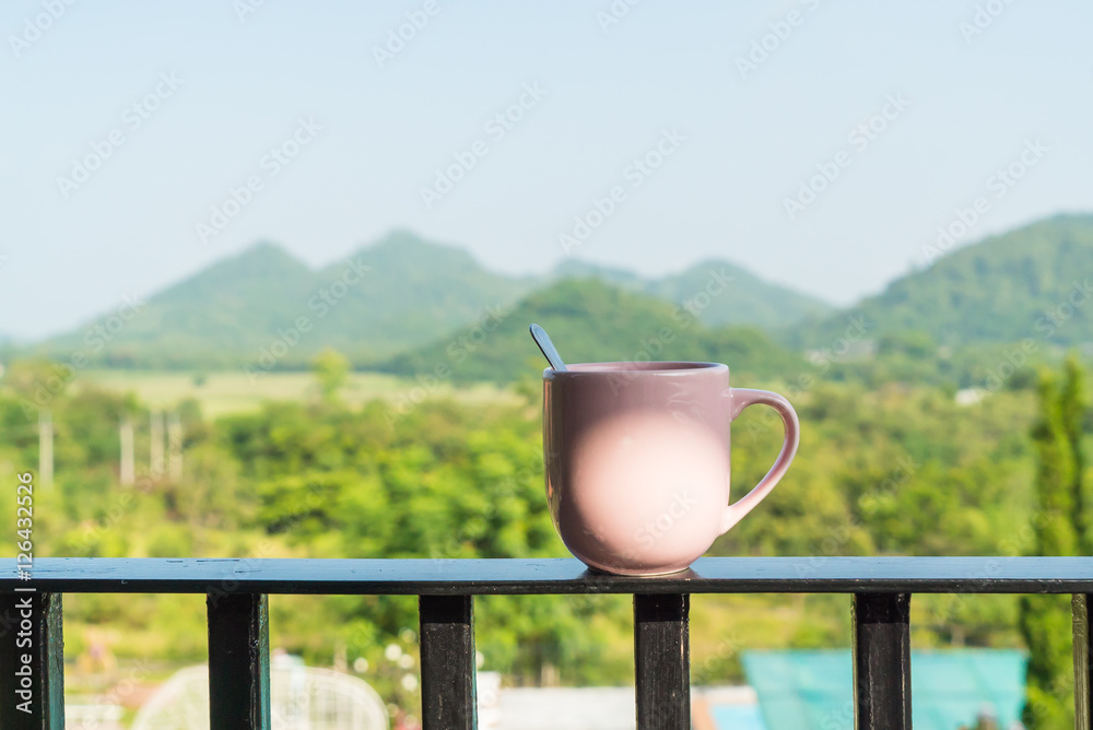 Obraz premium Cup of coffee on balcony in morning time with mountain view