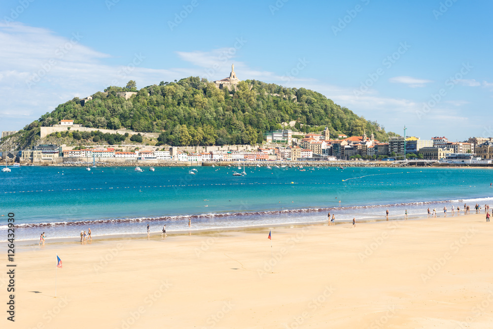 Donostia, San Sebastian. View to the mountain Urgull with the sculpture of Jesus Christ and the small island Santa Clara, The beach of La Concha is one of the famous urban beaches in Europe