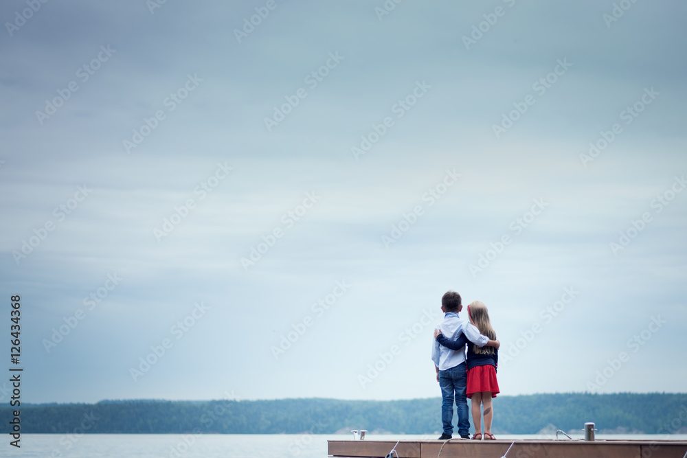 мальчик и девочка обнялись и смотрят на реку
