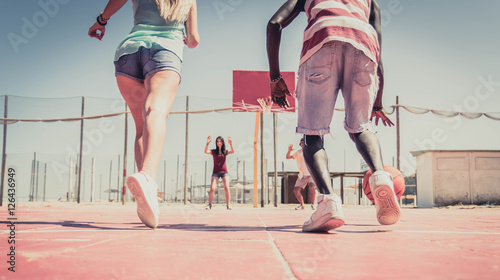 Group of multiracial friends playing basketball togheter. photo