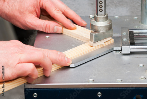 Craftsman working on frame in frame shop. Professional framer hand holding frame angle. Top view. Copy space
