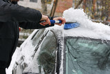 Man cleans a car from the snow.
