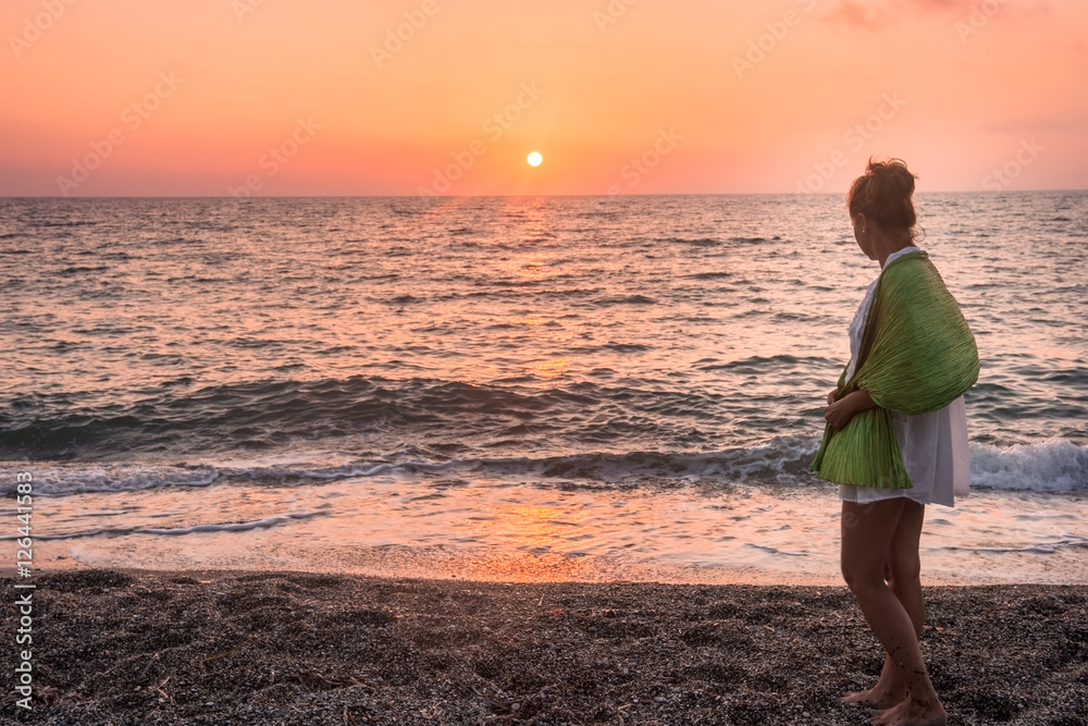 Adult woman taking a walk on the beach at magnificent sunset
