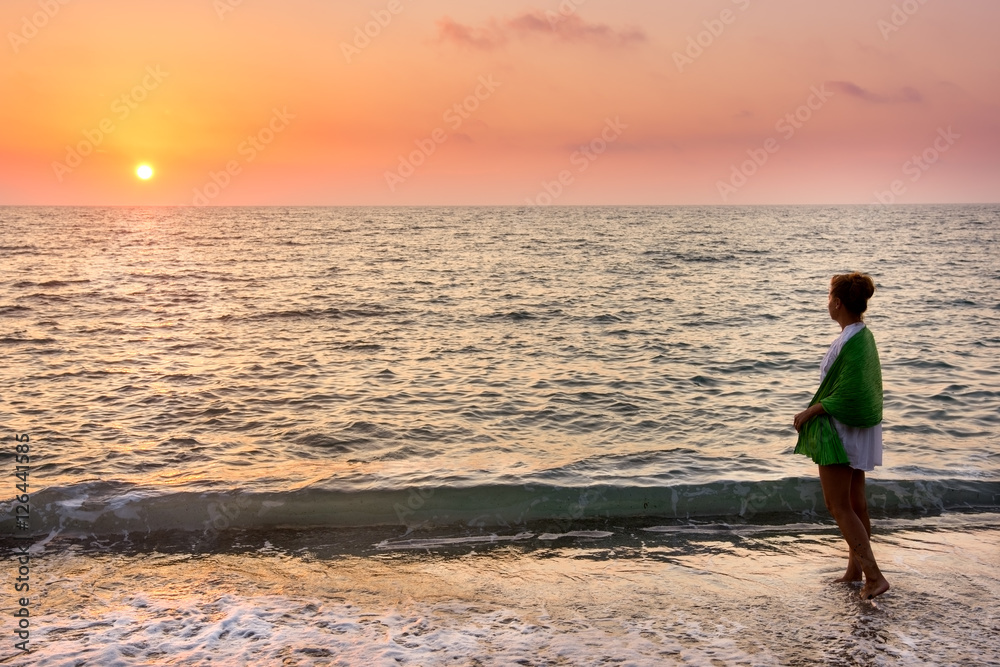 Adult woman on the beach at sunset in sea