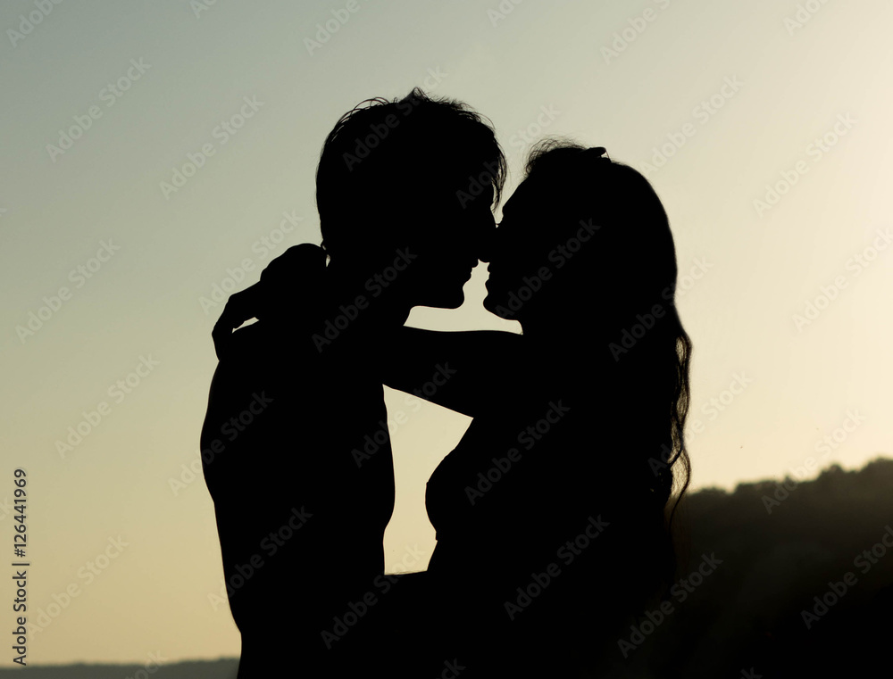 Couple kissing at the sea during sunset