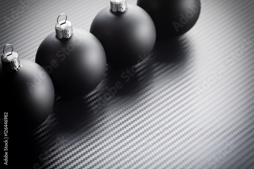 Black christmas baubles on carbon background