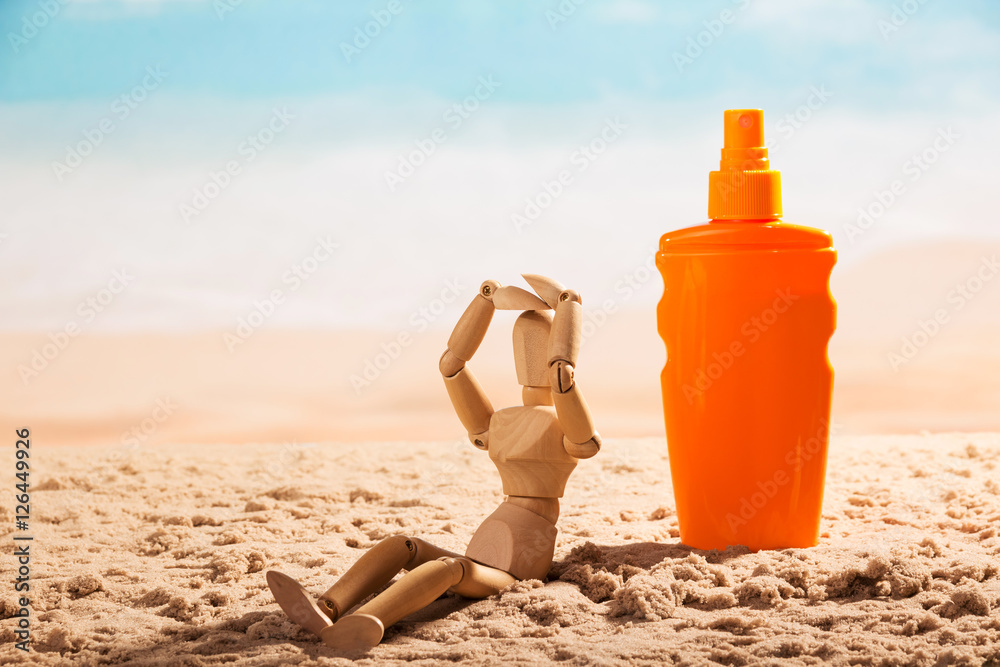 Sunscreen and wooden doll on the seashore. Sunscreen and wooden doll on the seashore.