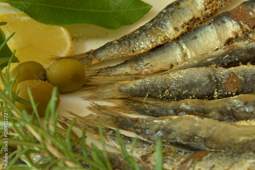 Salted anchovy with lemon, lemon leaf, rosemary and olives on plate