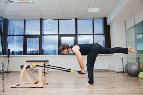 Man on pilates equipment. Fit and slim. Shows exercise