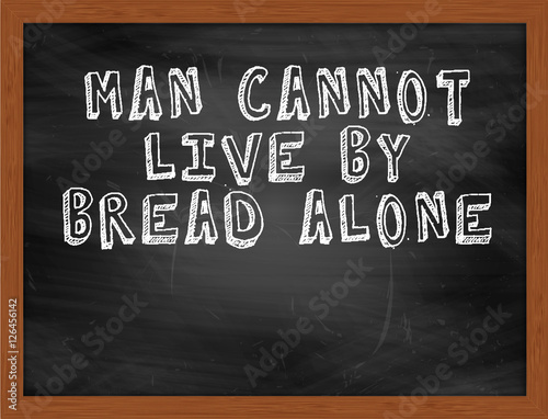 MAN CANNOT LIVE BY BREAD ALONE handwritten text on black chalkbo
