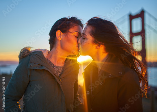 romantic lesbian couple passionately kissing by golden gate bridge