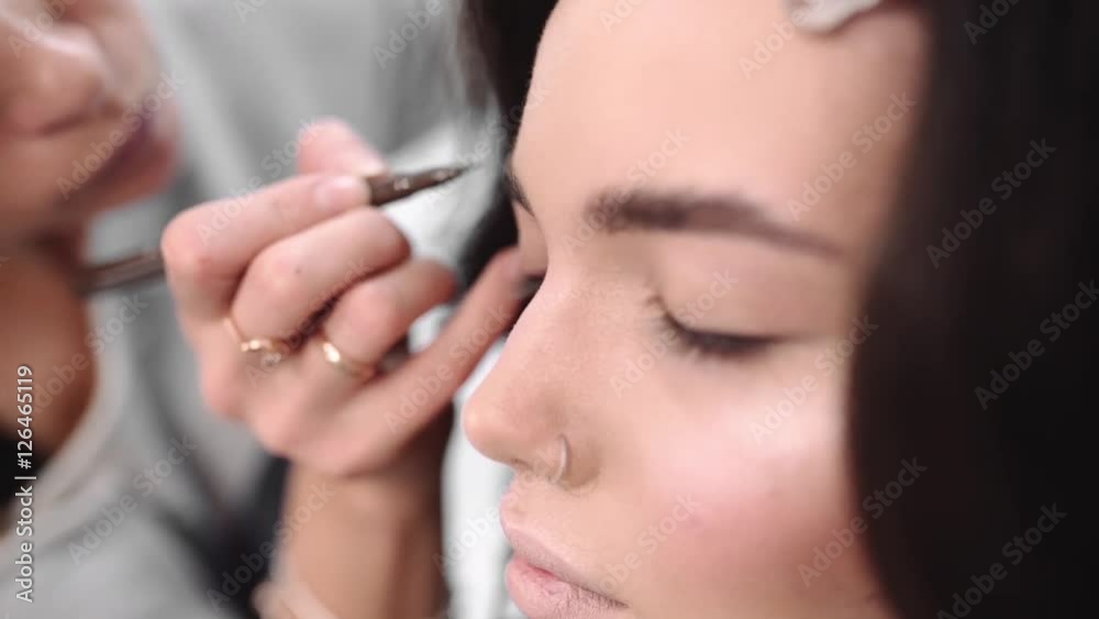 Make up artist paints eyebrows by pencil, Make up artist does make up for model, woman in beauty salon, photo model gets ready for photoshoot Make up artist paints eyebrows by pencil, Make up artist does make up for model, woman in beauty salon, photo model gets ready for photoshoot