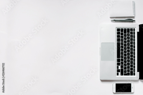 White office desk with laptop, smartphone and notebook . Top view with copy space, flat lay.
