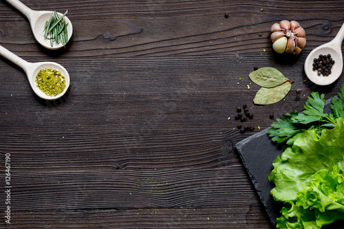 spices and fresh salad on dark wooden table top view