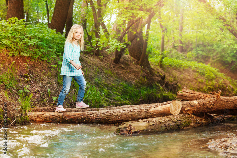 Little girl crossing log bridge in the forest Little girl crossing log bridge in the forest