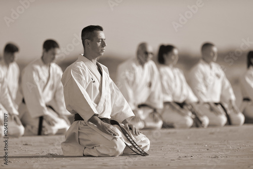 People in kimono sitting on the sand with their sensei on front